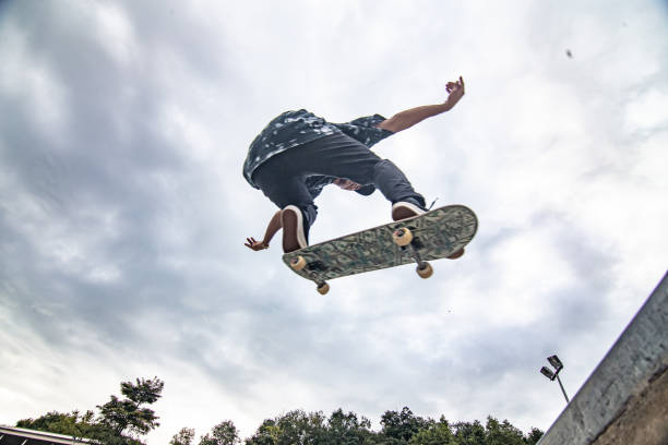 asiatischer skateboarder in aktion springen in die luft - skateboardfahren stock-fotos und bilder