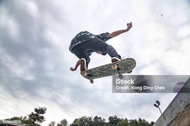 Asian Skateboarder In Action Jump In The Air Stock Photo - Download Image Now - Skateboarding, Skateboard, Skating