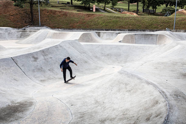 istock Asian skateboarder riding skateboard in skatepark pool 1319646451