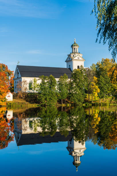 istock White church standing by a river with autumn colored trees 1319647338