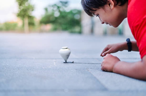 Closeup of a caucasian boy playing with a spinning top in the park Closeup of a caucasian boy playing with a spinning top in the park. spinning top stock pictures, royalty-free photos & images