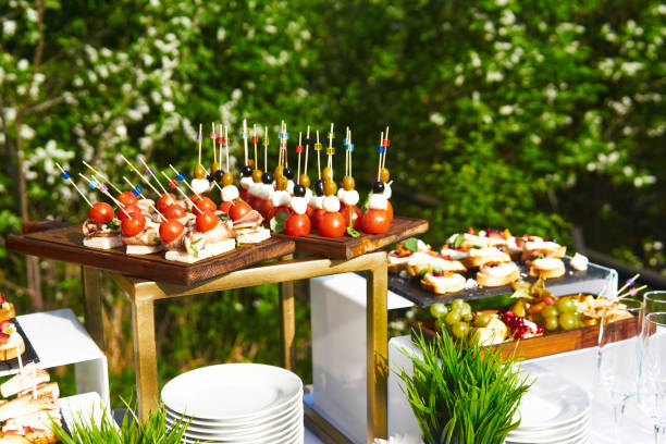 buffet al aire libre - canapés en palos de cóctel sobre el fondo de los árboles en flor - canape buffet cocktail food fotografías e imágenes de stock