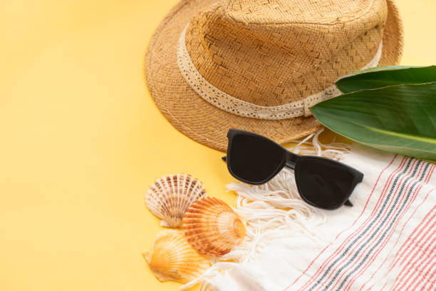 istock Hat, sun glasses, shells and beach towel on yellow background. 1319651970