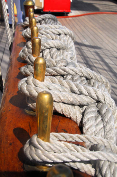 Ropes coiled and secured by bronze belaying pins on a pinrail - composed of a round handle and cylindrical shaft, the shaft is inserted into a hole on wooden pinrails- sailing ship.