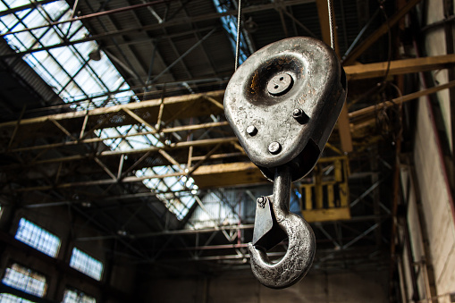 Crane hook for overhead crane in a factory building. Industrial interiors on the background. Lifting gear.