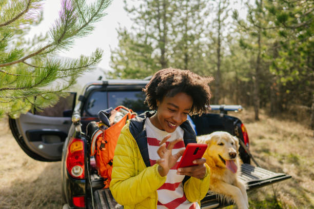 istock Young woman using mobile phone while on a road trip 1319657783