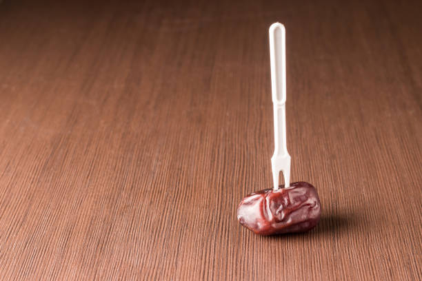 Single date fruit on a wooden table with a stuck fork