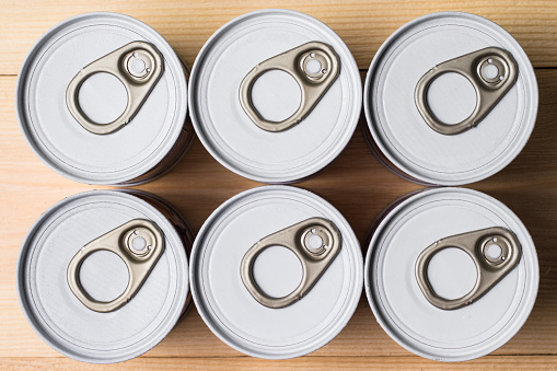 Stack of tin cans with a key, top view. Condensation has formed on the cans.