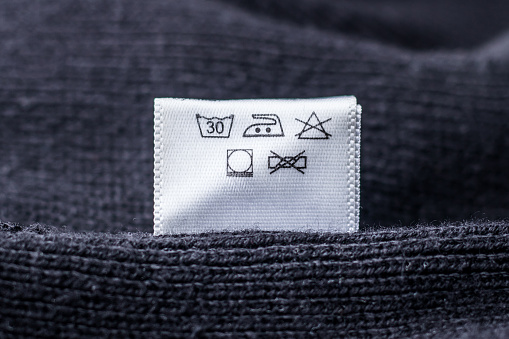 Label on clothes, black knitted sweater. Delicate care.