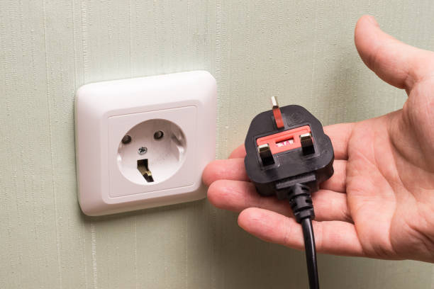 istock Different standards for electrical outlets. Unsuitable connector and plug in the hand of a person. Incompatibility, concept 1319659876
