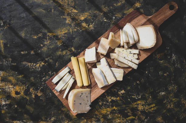istock Dairy products cheeses background. Cheeseboard with slices of cheeses on a dark rustic background 1319660842