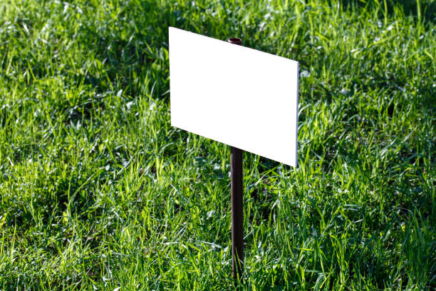 istock blank white sign mockup on green lawn background - close-up with selective focus 1319660900