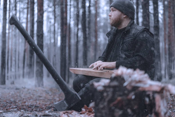A man with a beard cut down a tree with an axe. He stopped to rest and plays the traditional Finnish musical instrument Kantele. Late autumn or winter. A man with a beard cut down a tree with an axe. He stopped to rest and plays the traditional Finnish musical instrument Kantele. Late autumn or winter. psaltery stock pictures, royalty-free photos & images