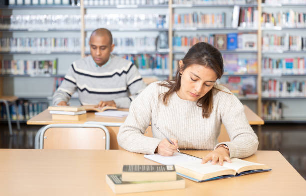 istock Young adult woman studying in public library 1319662339