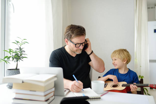istock Father freelancer working from home with laptop during quarantine. Naughty son distracts. Home office and parenthood at same time. Exhausted parent with hyperactive child. 1319662357
