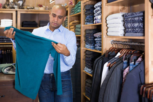istock Confident man choosing sweater in clothing store 1319663306