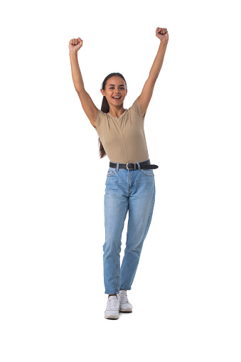 Full length portrait of casual latin girl standing with arms raised isolated on white background