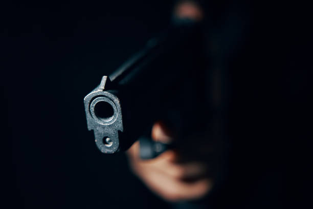Close-up of black pistol in hand. Gun pointed at camera in close-up. Pistol in hand in dark. Criminal with dangerous firearm. Attack or defense. gunman photos stock pictures, royalty-free photos & images