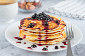 Delicious small pancakes drizzled with blueberry jam on a white plate