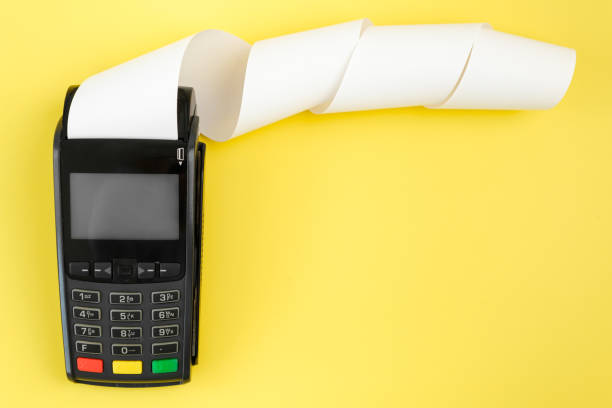 istock Payment terminal POS with a roll cash tape on the yellow background with copy space 1319667230