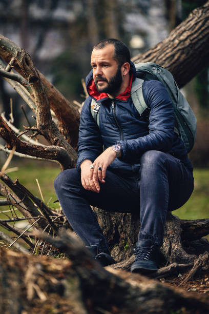 istock a handsome bearded man with a backpack sitting in the park and resting 1319667437