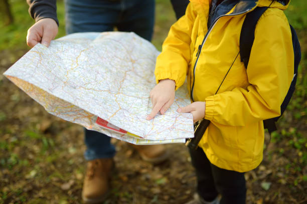 un écolier et son père mature font de la randonnée ensemble et explorent la nature. petit garçon avec papa regardant la carte pendant la course d’orientation en forêt. tourisme d’aventure, de scoutisme et de randonnée pour les enfants. - course dorientation photos et images de collection