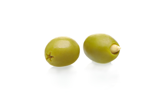 Two green olives stuffed with almonds isolated on white background. Healthy food concept.