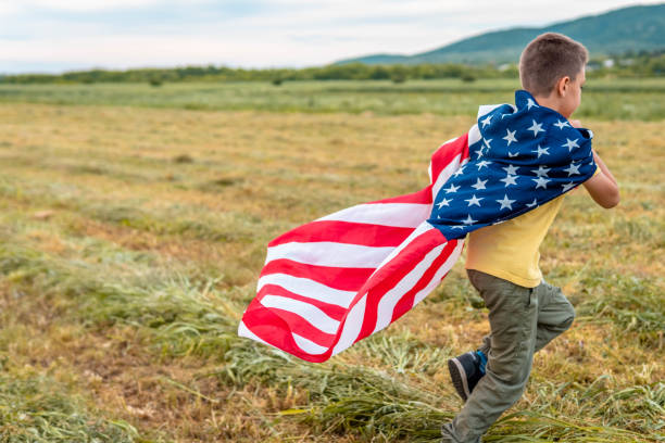 istock cheerful active little boy running and waving american flag 1319673743