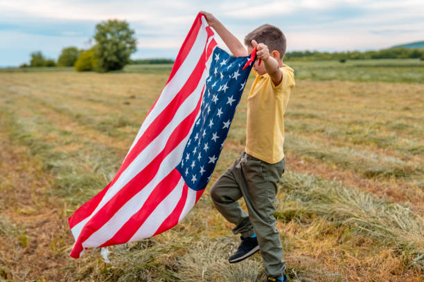 istock Cheerful active little boy running and waving american flag 1319673794