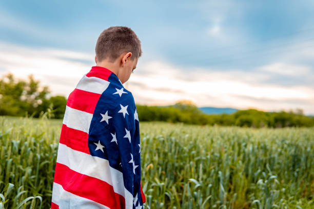istock Sad boy wrapped with american flag. 1319674058