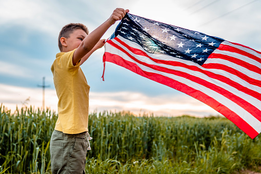 Photo of boy with American flag in nature.