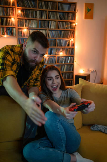 istock Young fun couple playing video games at home 1319675322