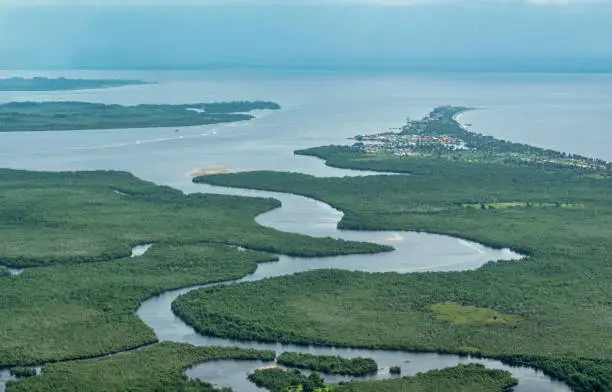Aerial view of the mouth of Congo River into the Atlantic Ocean near the small city of Banana Democratic Republic of Congo. Congo river is the second longest in Africa and world´s deepest river, it discharges 50,000 cubic meters of water per second into the Atlantic Ocean. The land at the horizon is the Cabinda Province of Angola.
