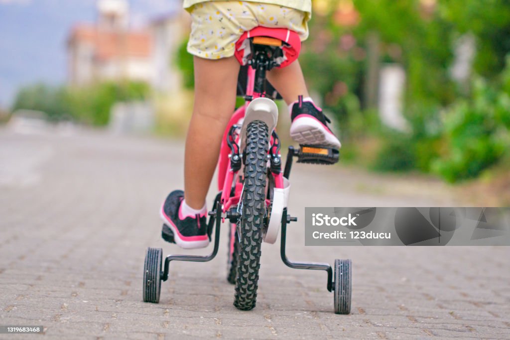 Detail view of little girl riding bicycle girl foots on the pedal selective focus Riding Stock Photo