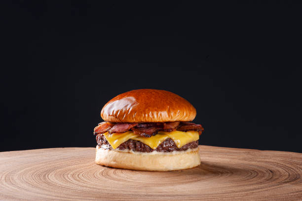 어두운 배경에 나무 테이블에 베이컨과 체다 치즈맛있는 쇠고기 버거. 복사 공간 - hamburger bun bread isolated 뉴스 사진 이미지