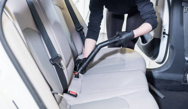 istock Worker cleans car interior with vacuum cleaner 1319687496