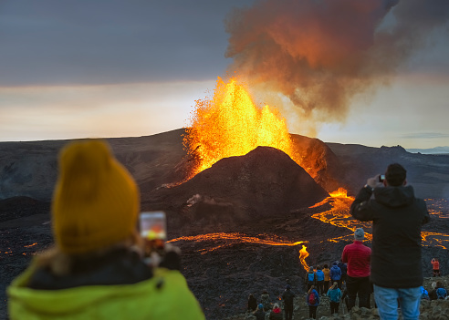 People observing the volcanic eruption of Fagradalsfjall in Iceland. Powerful Mother Nature. Hiking to view and experience the power of nature and running lava