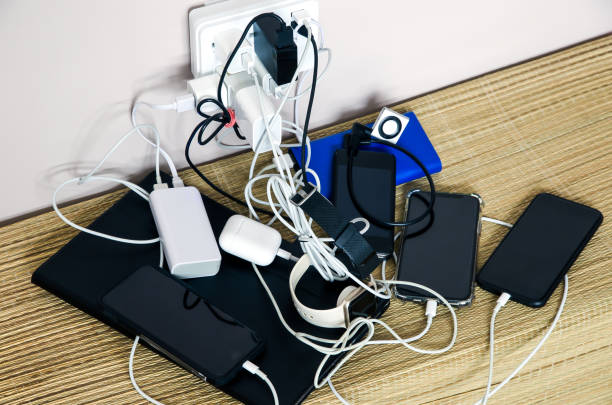 共有電力:電源アダプタと電源バンクが乱雑なケーブル接続で複数のデバイスを充電しています - mobile phone charging power plug adapter ストックフォトと画像