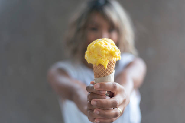istock Mixed-Race Female holding a bright yellow ice cream 1319694168