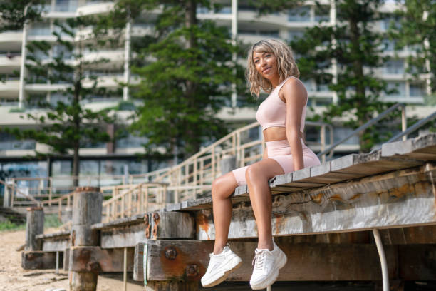 Attractive Black Female Sitting On Pier By Ocean