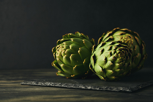 Still Life Background with Three Artichokes on Slate Cutting Board