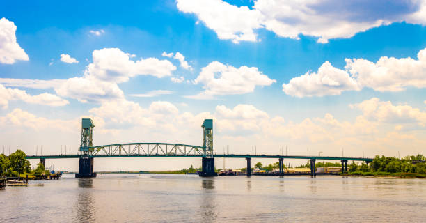 Cape Fear Memorial Bridge in Wilmington, NC The Cape Fear Memorial Bridge, an iconic arch bridge crossing the Cape Fear River in Wilmington, NC, during a partly cloudy day. wilmington north carolina stock pictures, royalty-free photos & images