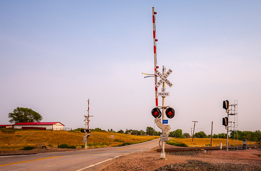 Early morning shot of a rural road with a railroad crossing.  The crossing arms are up, there are no trains, people or cars.