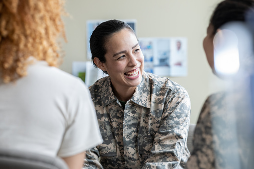 Mujer militar adulta sonriendo durante discusión de terapia de grupo photo