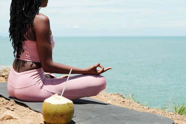 istock Young woman meditating on rock 1319717460