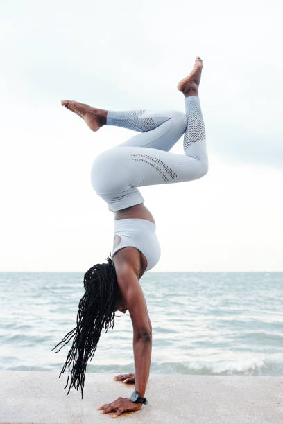 Sportswoman doing handstand on embarkment