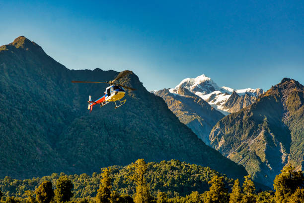 Helicopter flying off to the Glacier in the mountains Chopper lifting off the ground on the West Coast of New Zealand heading for the glaciers in the Southern Alps franz josef glacier photos stock pictures, royalty-free photos & images