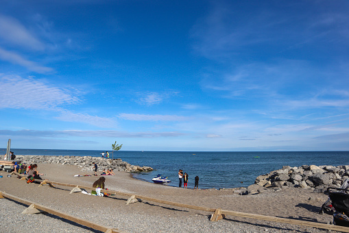 Toronto, Canada - May 23, 2021: People walking on the boardwalk at Kew-Balmy Beach on a sunny weekend during Ontario Covid-19 restrictions in Toronto, Canada