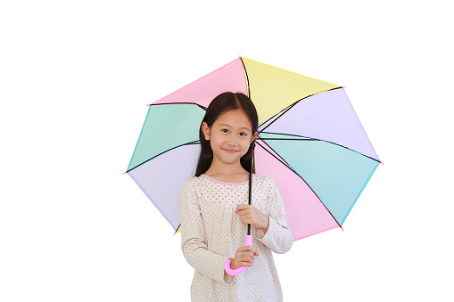 Portrait of happy Asian little girl with multicolored umbrella on white isolated background with clipping path. Kid holding colorful umbrella