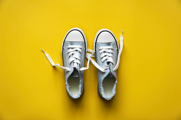 istock blue sneakers with white laces on a yellow background. 1319724906